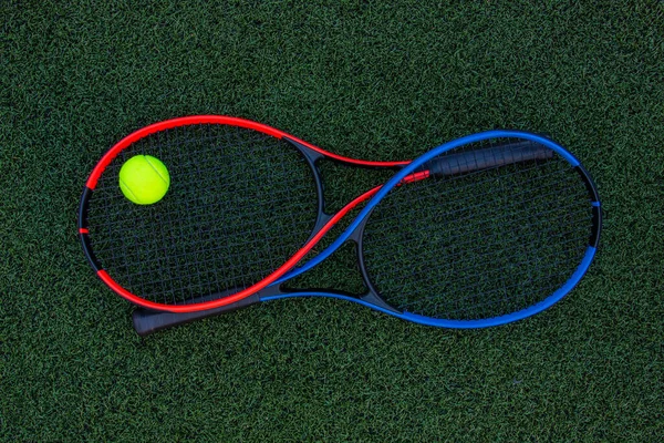 Yeşil çimlerde topları olan tenis raketleri.