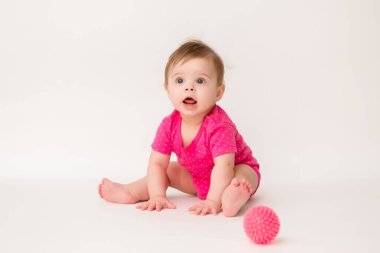 Pembe tişörtlü bir bebeğin yerde oturup lastik topla oynadığı uzay fotoğrafını kopyala