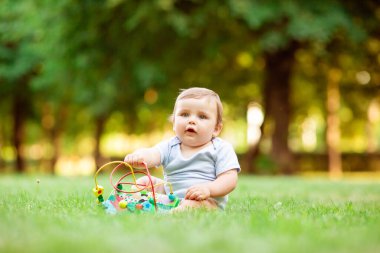 Sağlıklı şirin çocuk çimenlerde gelişim oyuncağıyla oynuyor.