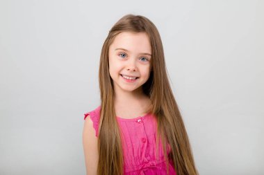 Beyaz arka planda pembe elbiseli küçük bir kızın portresi. Metnin için kopyalama alanı olan çocuk duyguları kavramı