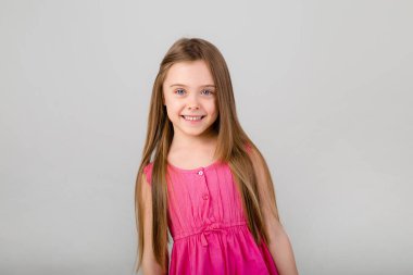Beyaz arka planda pembe elbiseli küçük bir kızın portresi. Metnin için kopyalama alanı olan çocuk duyguları kavramı
