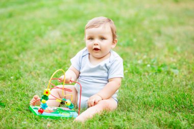 Sağlıklı şirin çocuk çimenlerde gelişim oyuncağıyla oynuyor.