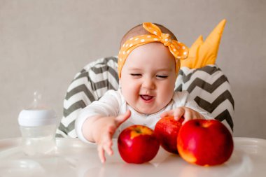 Uzun bir beslenme masasında oturan sevimli ve neşeli küçük bir kızın fotoğrafı.