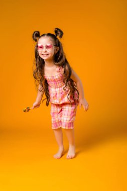 Sarı arka planda lolipopu olan neşeli bir kız. Metnin ya da ilanın için boşluk resmini yerleştirerek kopyala