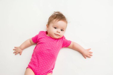 Pembe elbiseli 6 aylık sağlıklı bir kız çocuğu beyaz bir arka planda yatıyor. Metnin ya da ilanın için boşluk resmini yerleştirerek kopyala