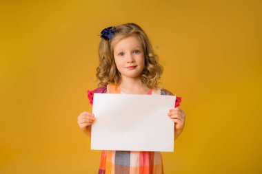Sarı arka planda beyaz bir çarşaf tutan bir kızın fotoğrafı. Reklam metniniz için boşluk resmini yerleştirerek kopyalayın