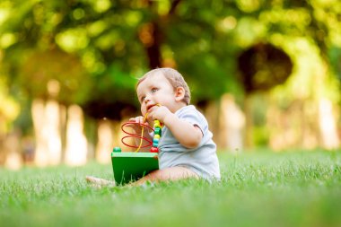 Sağlıklı şirin çocuk çimenlerde gelişim oyuncağıyla oynuyor.