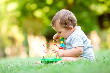 Sağlıklı şirin çocuk çimenlerde gelişim oyuncağıyla oynuyor.