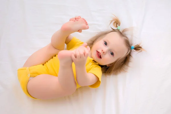 Menina Criança Amarelo Bodysuit Sorrisos Encontra Uma Cama Branca — Fotografia de Stock
