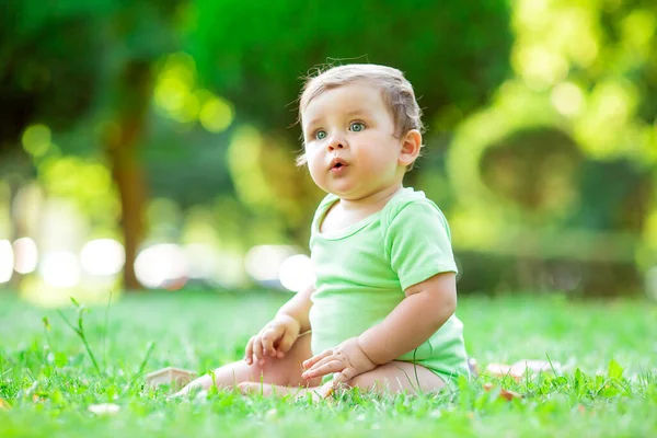穿着绿色紧身衣的可爱孩子坐在草地上 玩着长跑的立方体玩具 1年以下儿童发展概念 — 图库照片