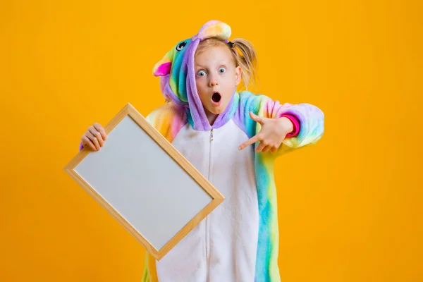 Szczęśliwa Dziewczynka Jednorożcu Kigurumi Unitard Trzyma Pustą Tablicę Tekst Żółtym — Zdjęcie stockowe