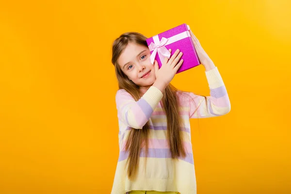 Зображення Щасливої Маленької Дівчинки Тримає Рожеву Подарункову Коробку Ізольовану Жовтому — стокове фото
