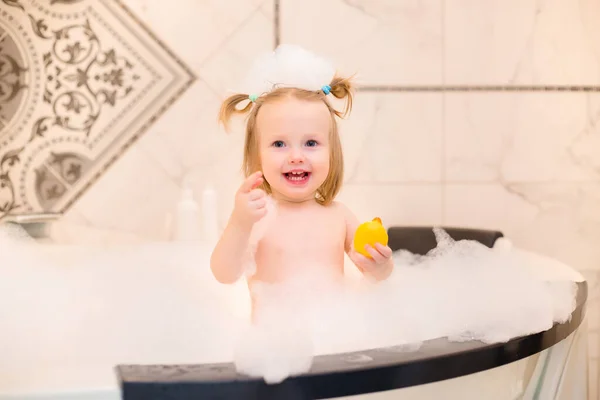 可爱的幼儿女孩在家里用泡沫洗澡 用橡胶鸭玩耍 — 图库照片