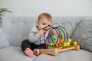 Küçük çocuk evdeki gri kanepede otururken gelişim oyunu oynuyor. 