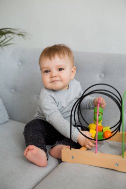 Küçük çocuk evdeki gri kanepede otururken gelişim oyunu oynuyor. 