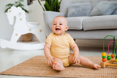 Sarı çizgili tulumlu şirin bebek halıda gelişim oyuncağıyla oynuyor. Çocuk gelişimi kavramı