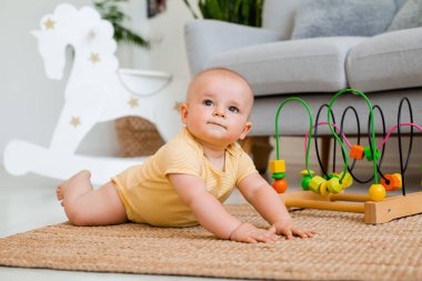 Sarı çizgili tulumlu şirin bebek halıda gelişim oyuncağıyla oynuyor. Çocuk gelişimi kavramı