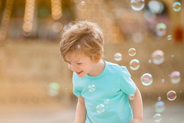 Mutlu kızıl çocuk, yaz eğlence parkında sabun köpüğüyle oynuyor. Çocuk yaşam tarzı ve mutluluk kavramı