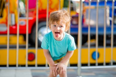 Mavi tişörtlü küçük mutlu çocuk yaz eğlence parkında yürüyüş yapıyor. Çocuk yaşam tarzı konsepti
