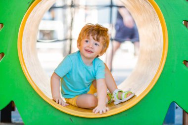 Little redhead boy of two years spending some quality time at children's playground. clipart