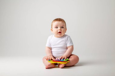Beyaz takım elbiseli tatlı çocuk gelişim oyuncağıyla oynuyor. Beyaz arkaplanda izole edilmiş resim