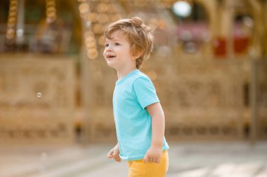 Mavi tişörtlü küçük mutlu çocuk yaz eğlence parkında yürüyüş yapıyor. Çocuk yaşam tarzı konsepti