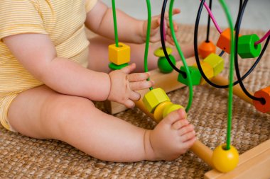 Sarı çizgili tulumlu şirin bebek halıda gelişim oyuncağıyla oynuyor. Çocuk gelişimi kavramı