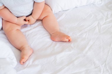 Beyaz battaniyenin üzerinde tatlı bir erkek bebeğin ayakları var.