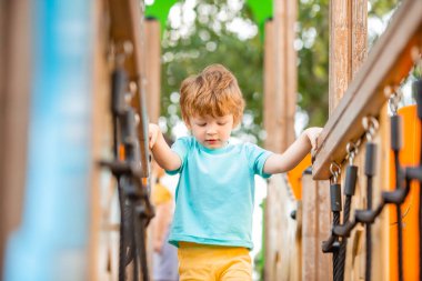 Neşeli kızıl saçlı çocuk renkli kaydırak ve çocuk parkına tırmanıyor.