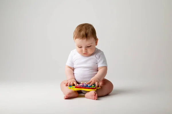 白いボディスーツのかわいい幼児の男の子は発達のおもちゃと遊ぶ 白い背景に孤立したイメージ — ストック写真