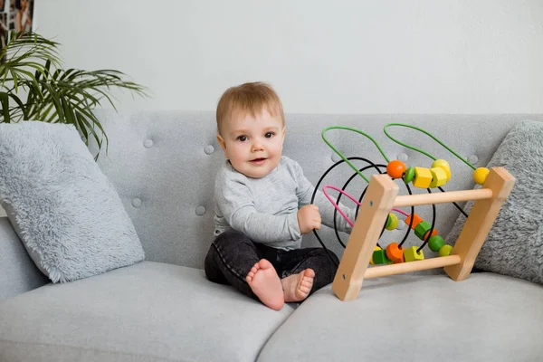 Küçük çocuk evdeki gri kanepede otururken gelişim oyunu oynuyor. 