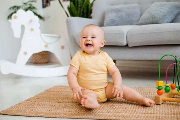 Sarı çizgili tulumlu şirin bebek halıda gelişim oyuncağıyla oynuyor. Çocuk gelişimi kavramı
