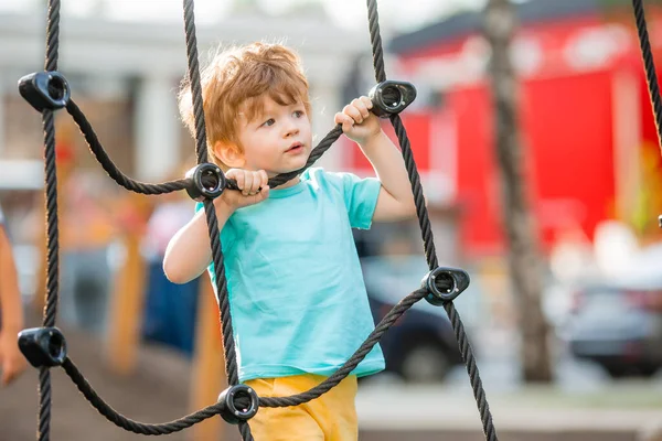 İki yıllık kızıl oğlan çocuk çocuk parkında oynuyor. Çocuk yaşam tarzı konsepti
