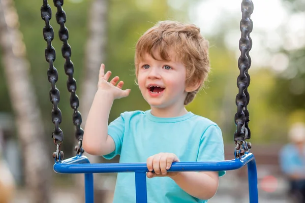 2 yıllık tatlı kızıl çocuk, çocuk parkında salıncakta sallanırken eğleniyor.