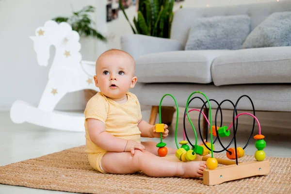 Sarı çizgili tulumlu şirin bebek halıda gelişim oyuncağıyla oynuyor. Çocuk gelişimi kavramı