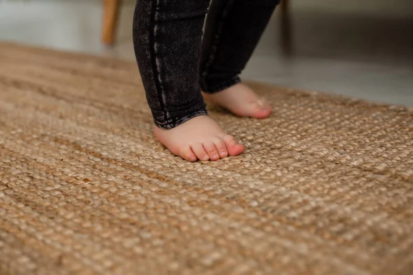 Doğal malzemelerden yapılmış halının üzerinde çocuk ayakları. Çevre dostu ev ürünleri kavramı