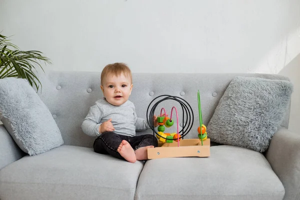Küçük çocuk evdeki gri kanepede otururken gelişim oyunu oynuyor. 
