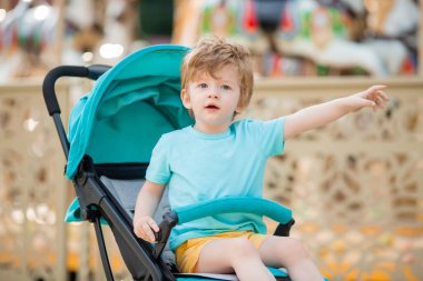İki yaşındaki tatlı kızıl çocuk mavi bir bebek arabasında oturuyor. 
