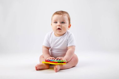Beyaz takım elbiseli tatlı çocuk gelişim oyuncağıyla oynuyor. Beyaz arkaplanda izole edilmiş resim