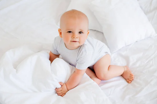 Φωτογραφία Ενός Χαρούμενου Αγοριού Μηνών Λευκό Κοστούμι Στο Κρεβάτι — Φωτογραφία Αρχείου