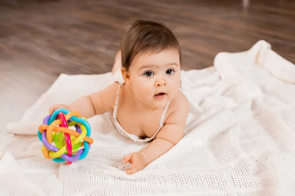 Cute Toddler Girl In White Dotted Top Lays On Wooden Floor On Soft Knitted Plaid And Play With Developmental Toy Stock Images Page Everypixel