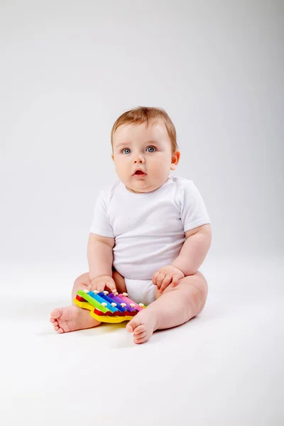 白いボディスーツのかわいい幼児の男の子は発達のおもちゃと遊ぶ 白い背景に孤立したイメージ — ストック写真