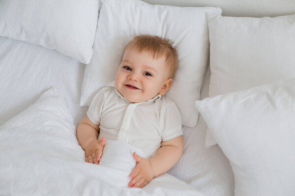 Cute happy little toddler boy laying in bed 