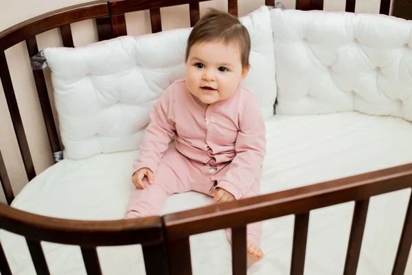 Cute Dziewczynka Maluch Różowym Onesie Jej Drewniane Łóżko Miękkimi Białymi — Zdjęcie stockowe