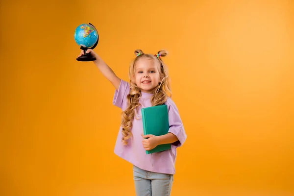 Wesoła Blondynka Trzymająca Kulę Księgę Rękach Odizolowane Pomarańczowym Tle Dziecięce — Zdjęcie stockowe