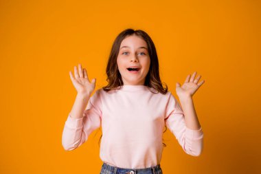 Stüdyoda turuncu arka planda sevimli küçük bir kız.