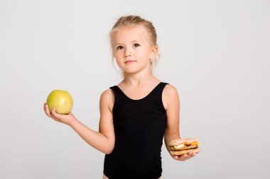 Gülümseyen kız bir elma ve bir hamburger tutuyor. Sağlıklı yemek seçiyorum, fast food yok, yazı için yer var.