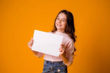 Stüdyoda turuncu arka planda sevimli küçük bir kız.