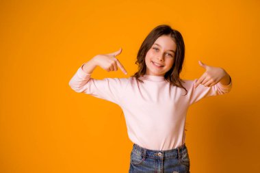 Stüdyoda turuncu arka planda sevimli küçük bir kız.