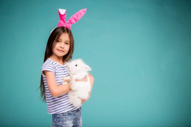 Sevimli küçük kız elinde tavşan tutuyor. 